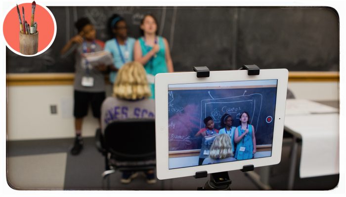 A closeup of an iPad filming three students performing a skit